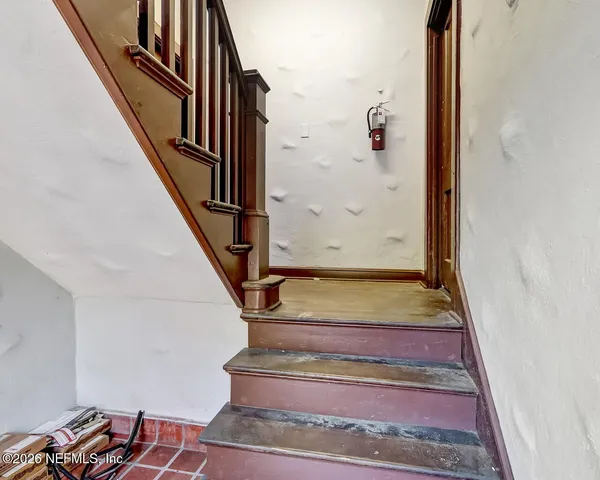 a view of staircase with wooden floor and lots of frames on wall