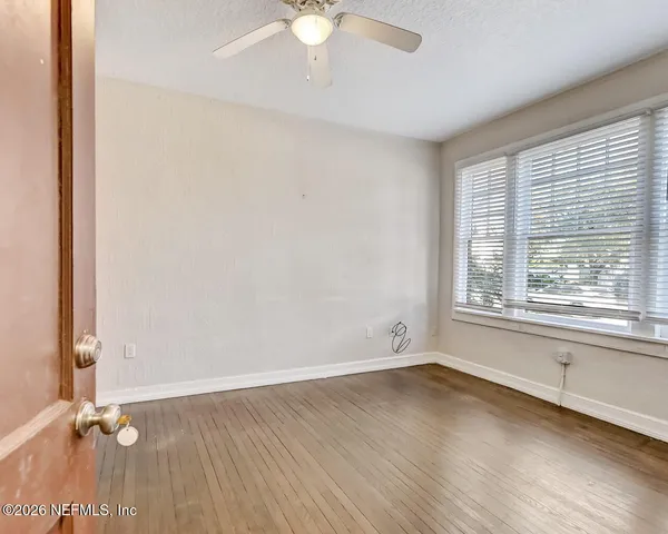 an empty room with wooden floor and windows