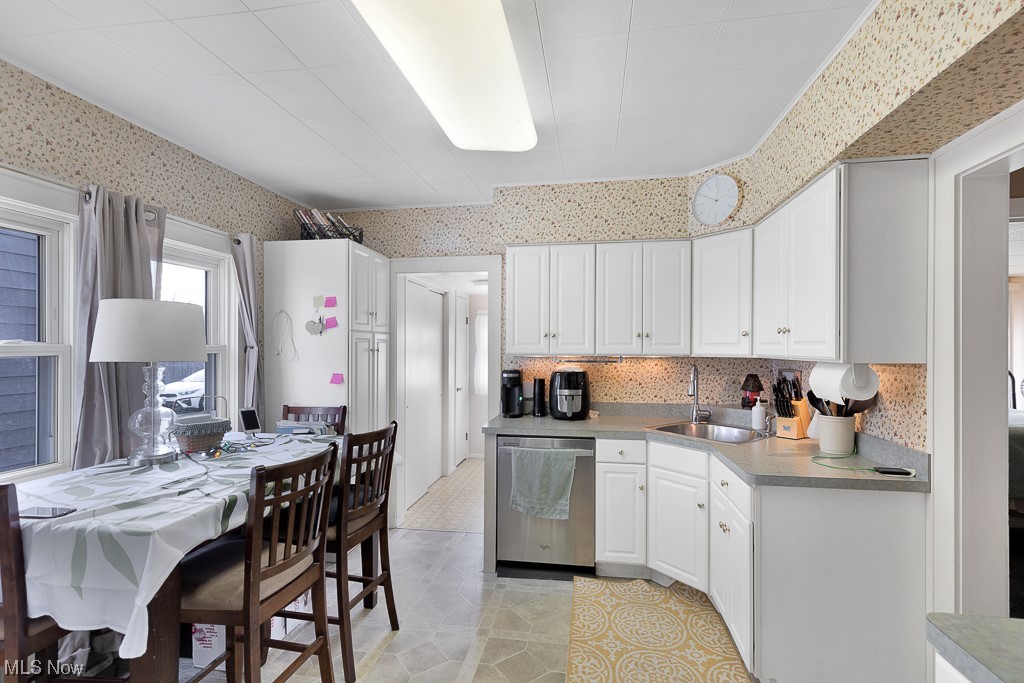 8007 Snow Road Parma, OH 44129 - Photo 5 of 25 Kitchen with light tile floors, white cabinets, backsplash, dishwasher, and sink