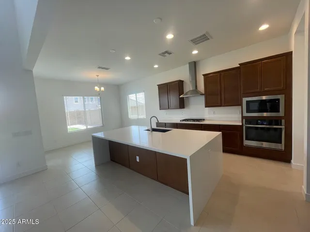 a large kitchen with stainless steel appliances a large counter top a stove and a refrigerator