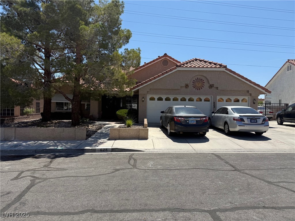 View of front of home featuring a tile roof, an attached garage, driveway, and stucco siding