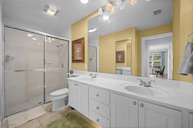 a bathroom with a double vanity sink toilet mirror and shower