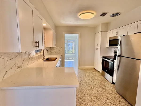 a large white kitchen with a refrigerator a sink and a stove
