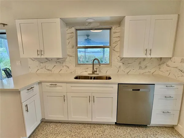 a kitchen with white cabinets and sink