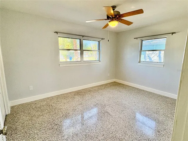 an empty room with windows and fan