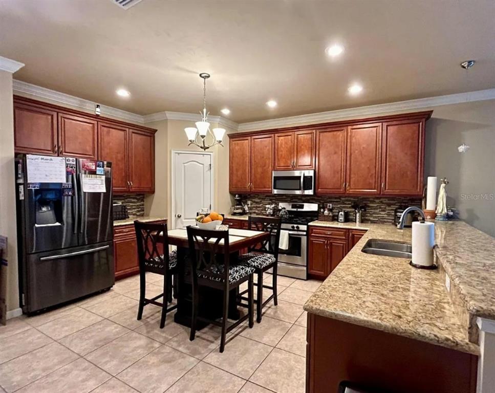 9883 Northwest 17th Road Gainesville, FL 32606 - Photo 11 of 11 a kitchen with stainless steel appliances granite countertop a stove top oven a sink a dining table and chairs