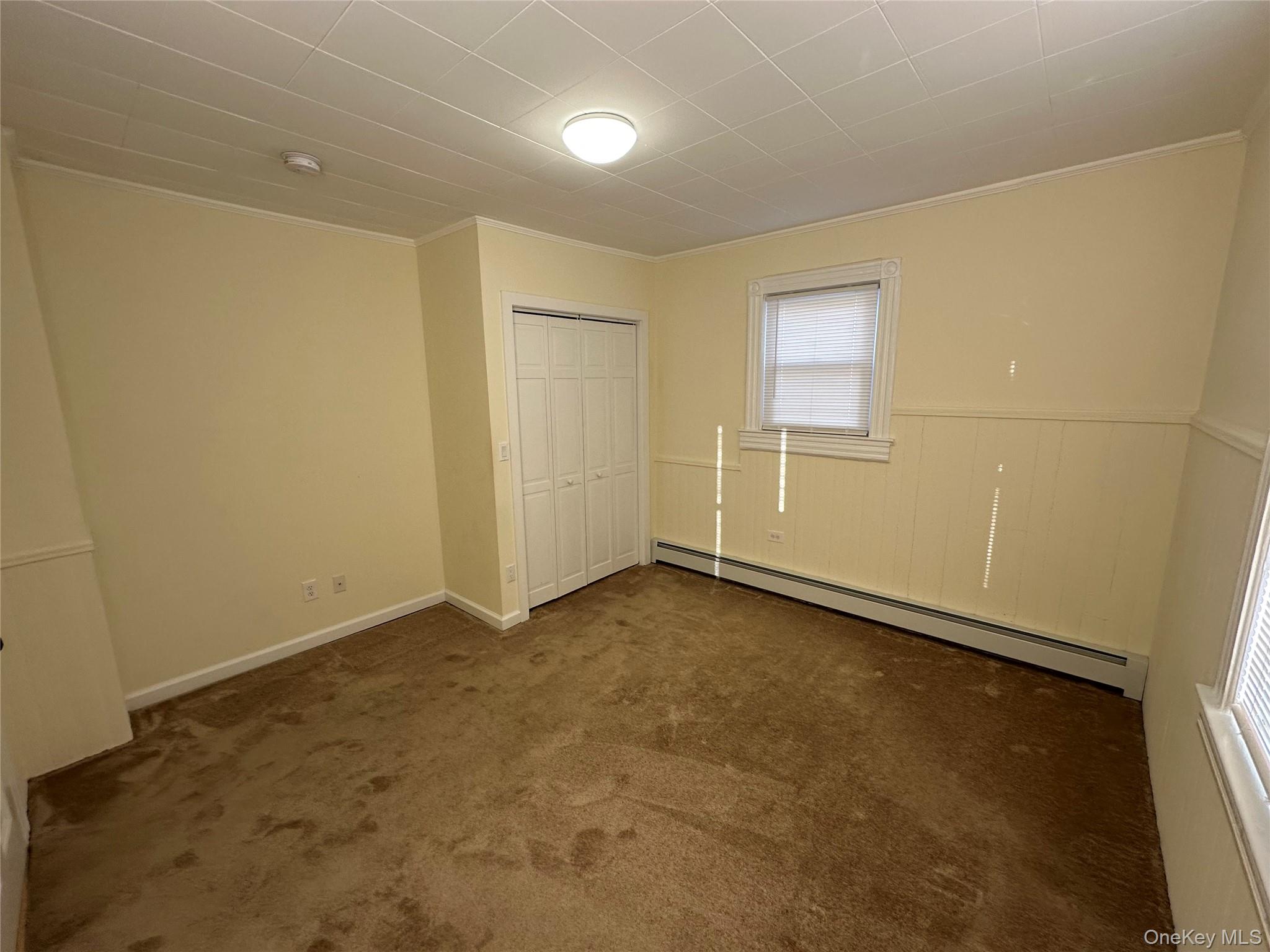 18 West Maple Avenue Suffern, NY 10901 - Photo 12 of 24 bedroom with baseboard heating, a closet, dark carpet, and crown molding