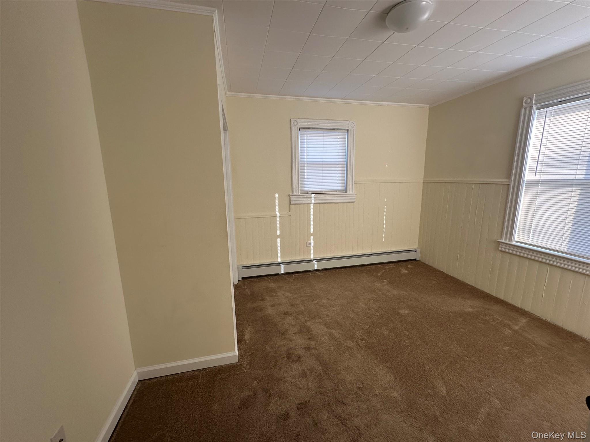 18 West Maple Avenue Suffern, NY 10901 - Photo 14 of 24 Another view of bedroom with dark carpet, a wainscoted wall, a baseboard heating unit, and crown molding