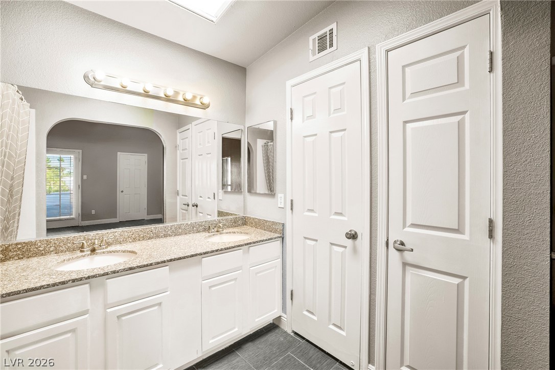 3311 Sunfish Drive, Unit D Henderson, NV 89014 - Photo 11 of 21 Double vanity with stone counters provides ample space in this well-appointed bathroom.
