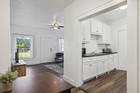a open kitchen with granite countertop a stove a sink a window and white cabinets