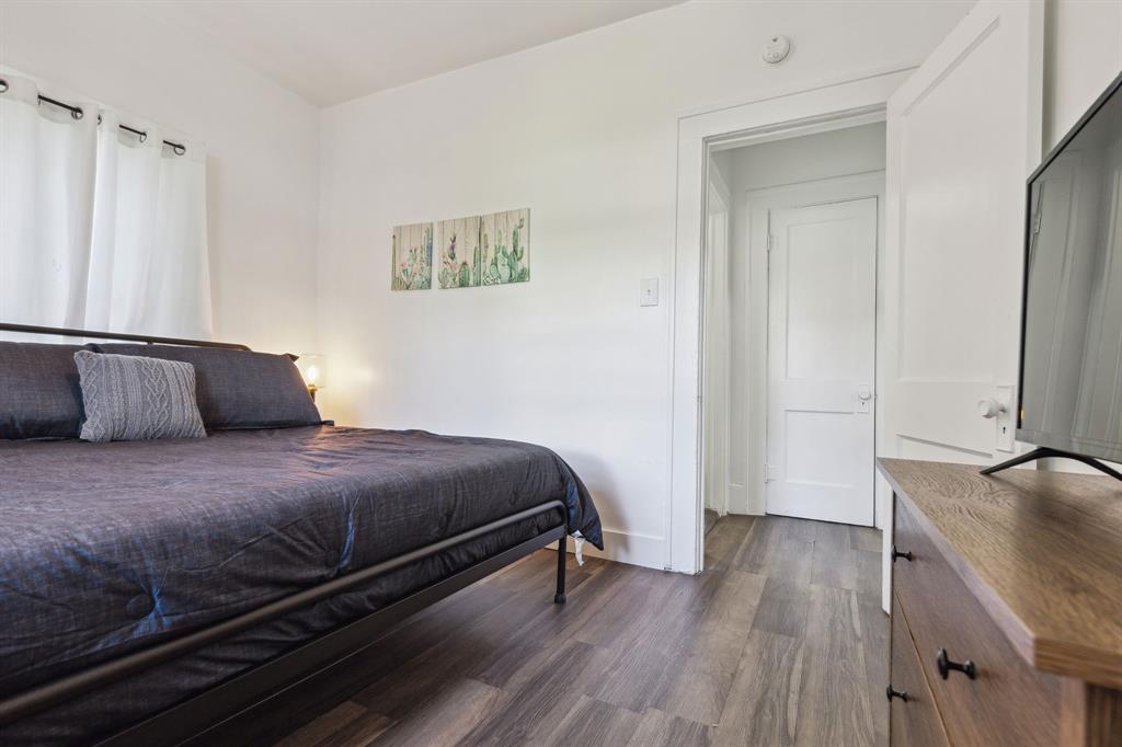 112 West Eighth Street Dallas, TX 75208 - Photo 20 of 34 a bedroom with a bed and wooden floor