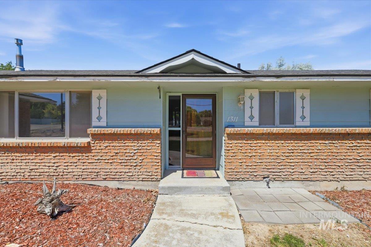 1311 North Middleton Road Nampa, ID 83651 - Photo 2 of 49 Exterior elevation featuring brick veneer siding, light blue painted siding, a dark asphalt shingle roof, and decorative white shutters