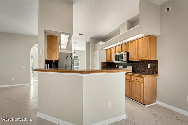 a kitchen with stainless steel appliances granite countertop a stove a sink and a microwave