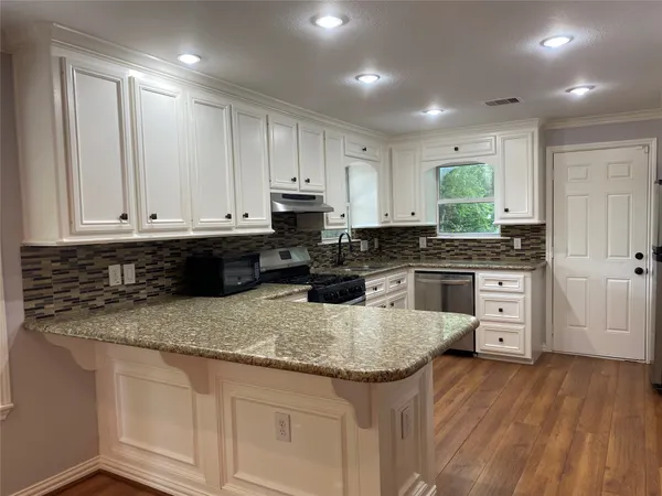 a kitchen with granite countertop a sink a stove and cabinets
