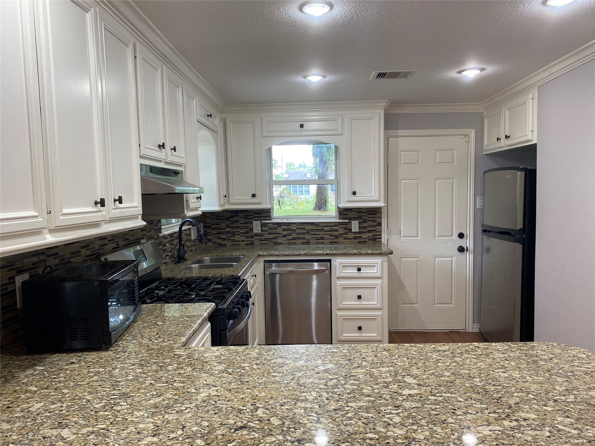 819 Eubanks Street Houston, TX 77022 - Photo 4 of 15 a kitchen with stainless steel appliances granite countertop a stove a sink and a refrigerator