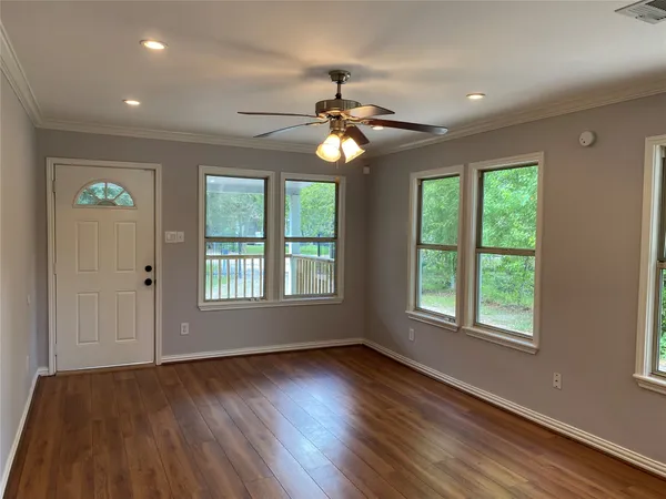 a view of an empty room with wooden floor and a window