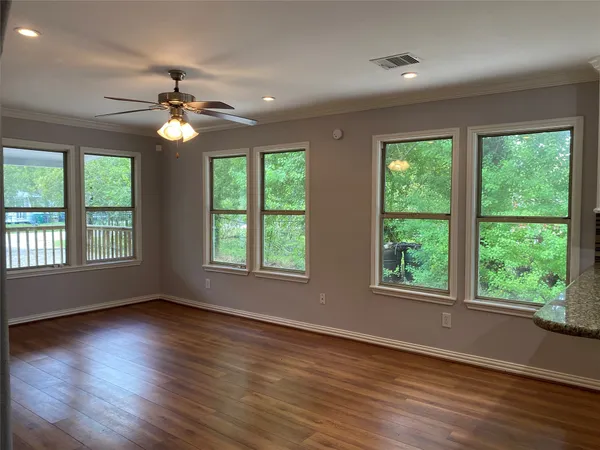 a view of empty room with wooden floor and fan