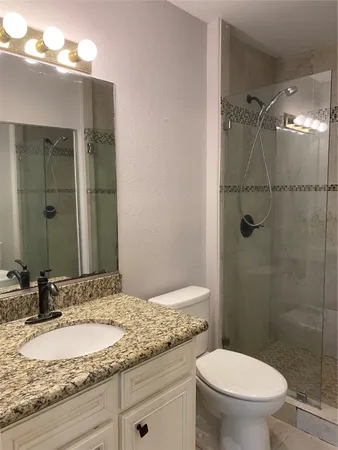 a bathroom with a granite countertop sink toilet and shower