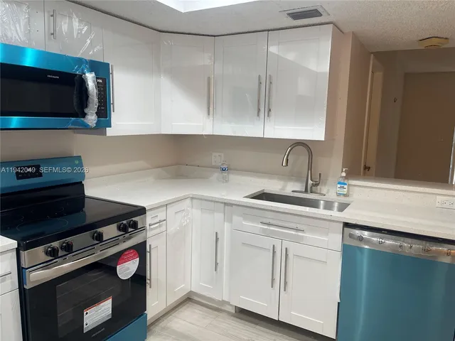 a kitchen with white cabinets and appliances