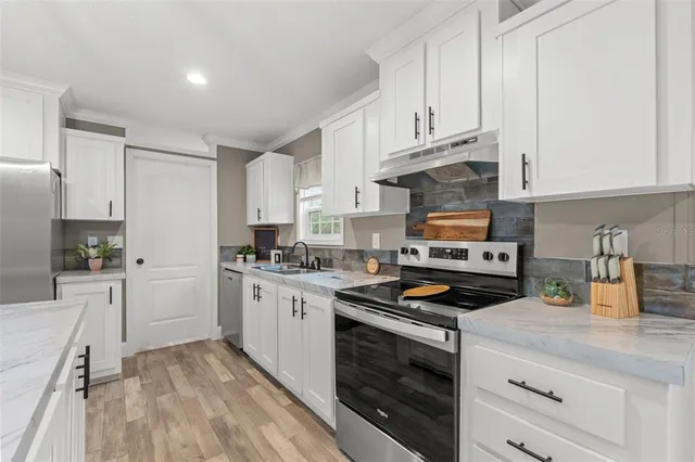 a kitchen with stainless steel appliances granite countertop a stove white cabinets a sink and dishwasher