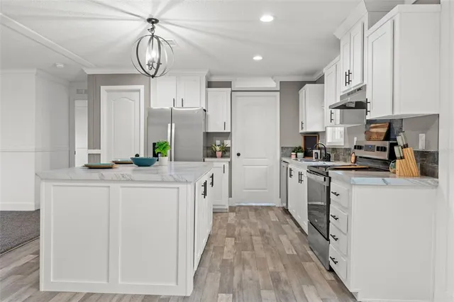 a kitchen with stainless steel appliances kitchen island granite countertop a stove a sink and a refrigerator
