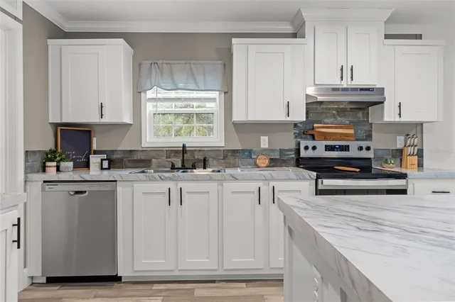a kitchen with stainless steel appliances granite countertop a stove a sink and a microwave