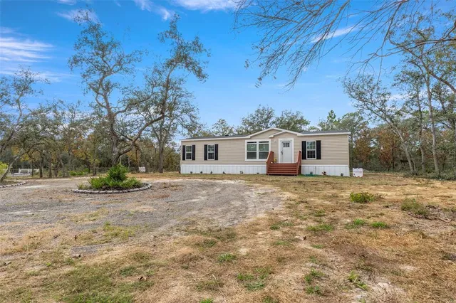 a view of a yard in front of a house with a large tree