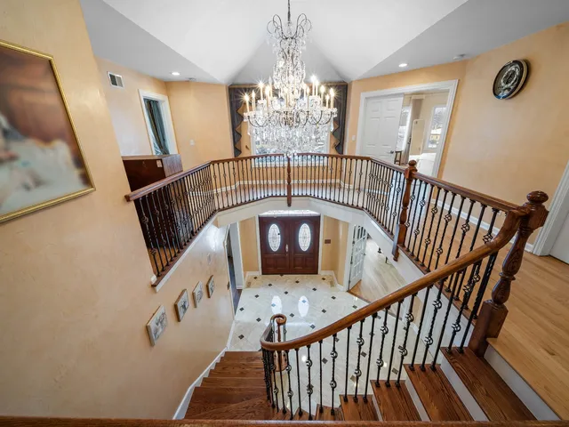 a view of staircase with railing and a chandelier