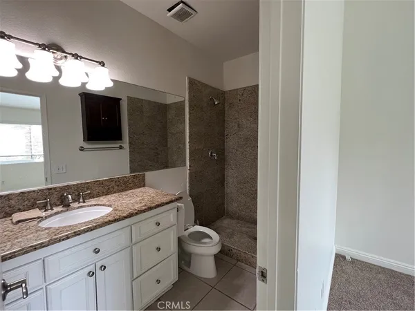 a bathroom with a granite countertop sink mirror toilet and shower