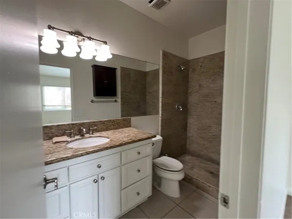 a bathroom with a granite countertop sink a toilet and shower