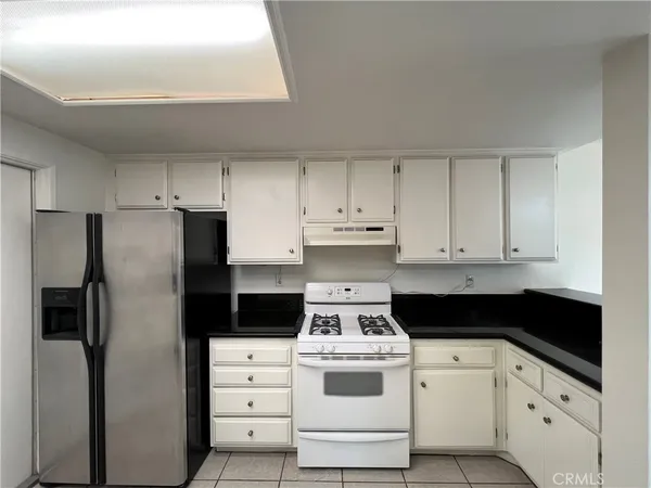 a kitchen with granite countertop white cabinets sink and stainless steel appliances