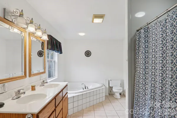 a bathroom with a granite countertop sink a toilet a mirror and shower