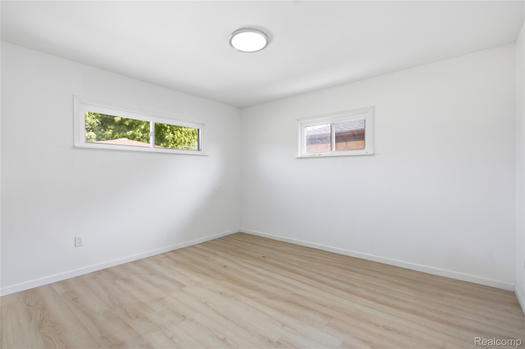 17544 Evergreen Road Detroit, MI 48219 - Photo 13 of 16 White walls with two distinct window styles, wood-finish flooring, and a flush-mount ceiling light fixture