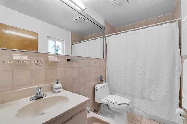 a bathroom with a sink a toilet and shower curtain