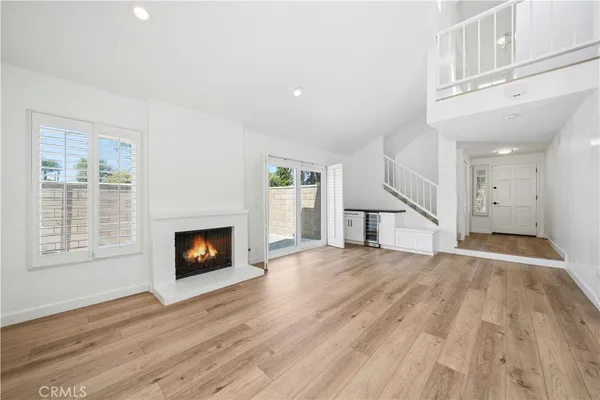 a view of an empty room with wooden floor fireplace and a window