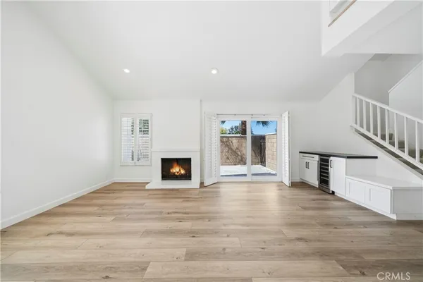 a view of an empty room with wooden floor fireplace and a window