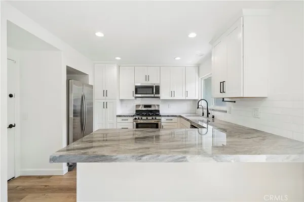 a kitchen with stainless steel appliances granite countertop a sink refrigerator and cabinets