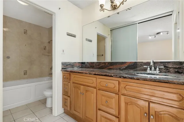 a bathroom with a granite countertop sink a toilet a mirror and bathtub