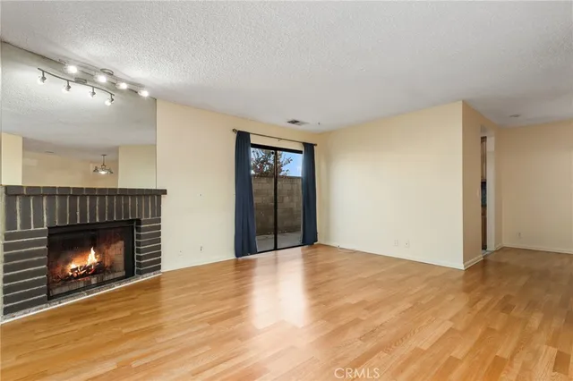 a view of an empty room with wooden floor fireplace and a window