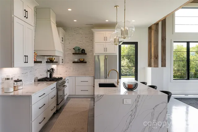 a kitchen with kitchen island granite countertop a stove a sink a refrigerator and a window