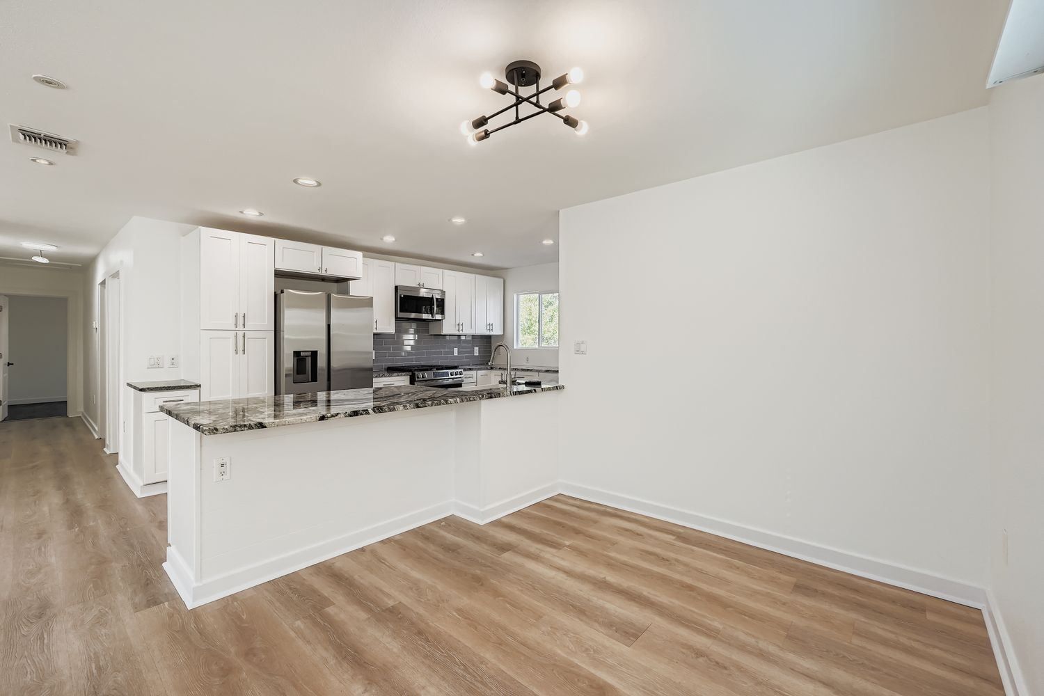 112 Tenorio Street Kyle, TX 78640 - Photo 3 of 11 a kitchen with stainless steel appliances kitchen island granite countertop a refrigerator a stove a sink and white cabinets with wooden floor