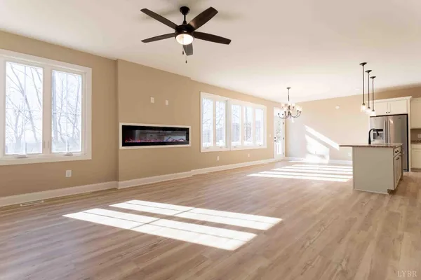 a view of a livingroom with wooden floor a ceiling fan and windows