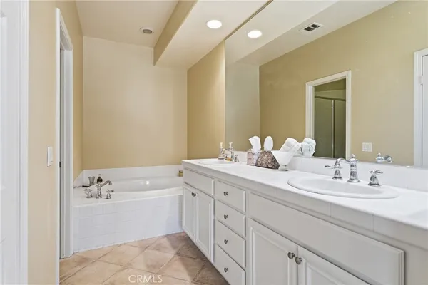 a bathroom with a double vanity sink mirror and bathtub