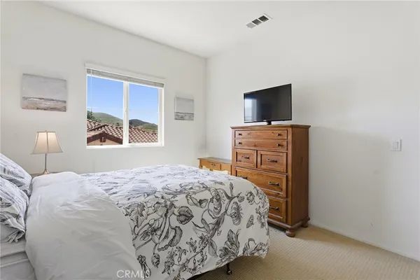 a bedroom with a bed and a flat tv screen on a dresser