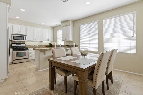 a kitchen with stainless steel appliances granite countertop a table chairs sink refrigerator and cabinets