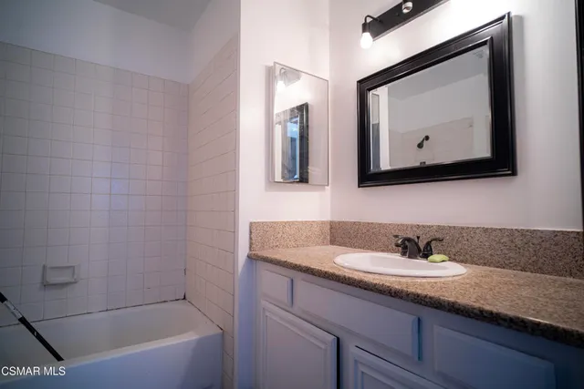 a bathroom with a tub a sink and mirror