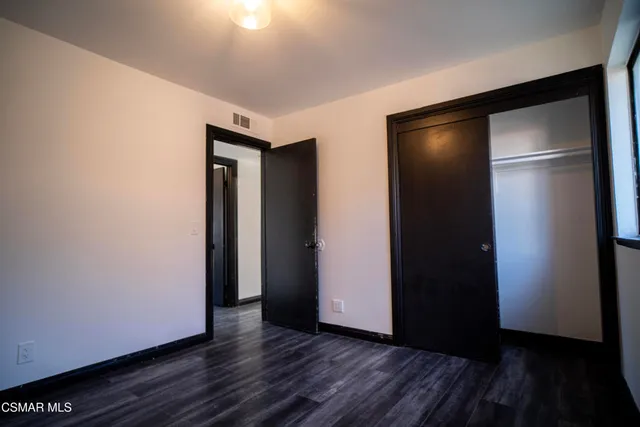 a view of an empty room with wooden floor and closet