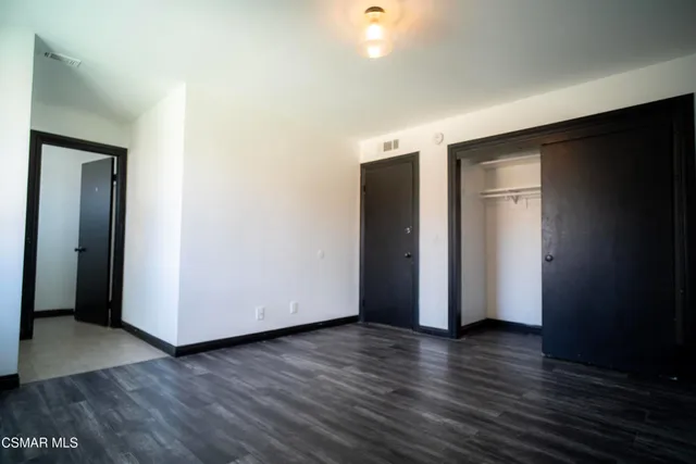 a view of an empty room with wooden floor and closet