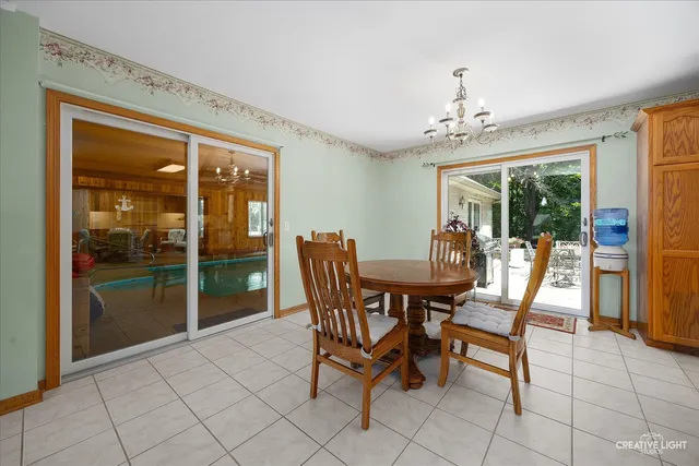 a dining room with furniture a chandelier and glass door