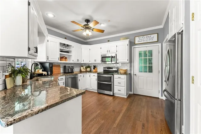 a kitchen with stainless steel appliances granite countertop hardwood floor sink stove dining table and chairs